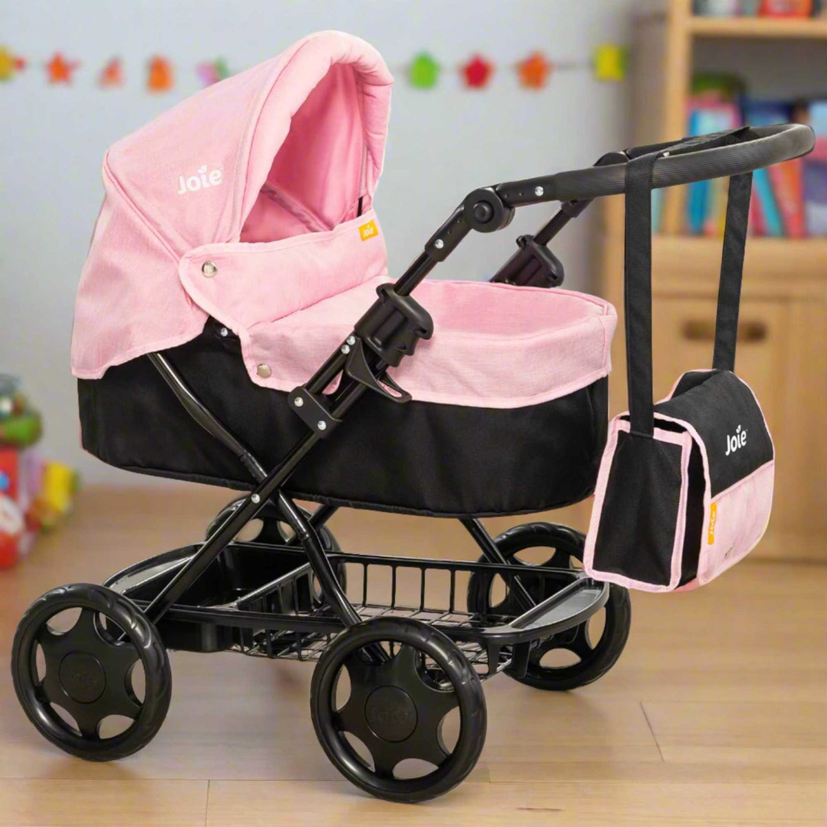 Joie Junior Classic Pram in pink and black, featuring a vintage design, includes a handheld parasol and a matching changing bag, perfect for children to enjoy sophisticated doll play and outings.