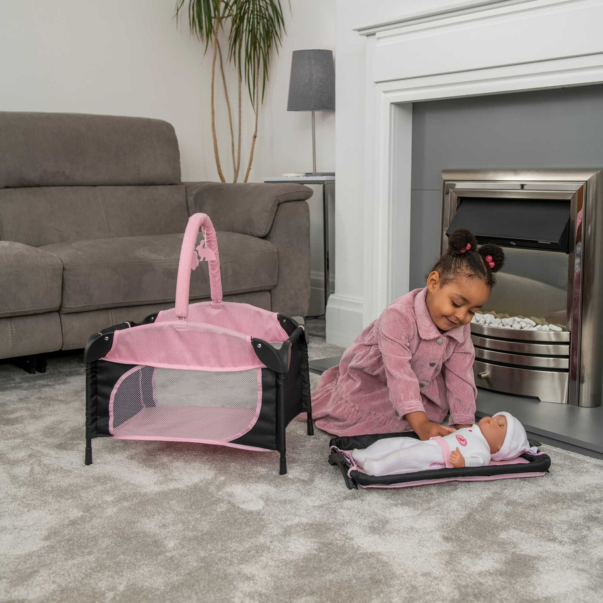 Joie Sleep &amp; Dream Dolls Travel Cot, a compact and foldable design in pink and grey, featuring breathable mesh sides and a sturdy frame, ideal for children to use for their dolls during playtime and travel