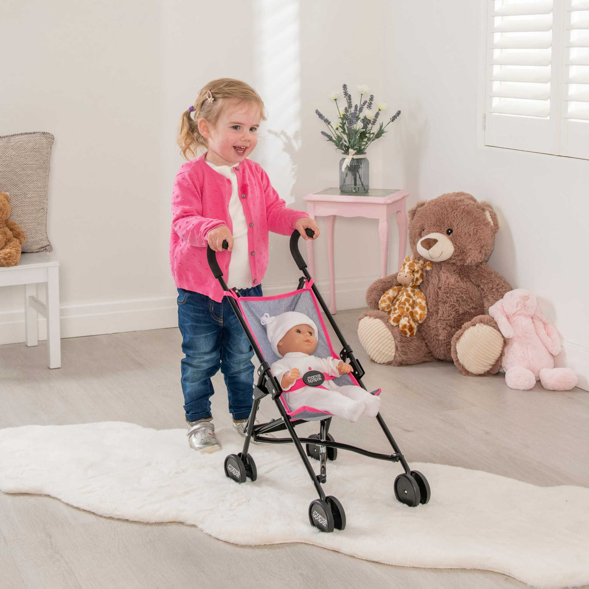 Mamas &amp; Papas Junior Doll Stroller in pink and grey, featuring a foldable and lightweight design for easy storage and portability, ideal for children&#39;s imaginative play with dolls.