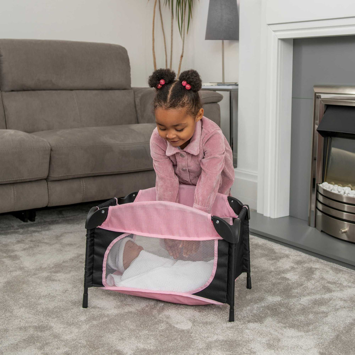 Joie Sleep &amp; Dream Dolls Travel Cot, a compact and foldable design in pink and grey, featuring breathable mesh sides and a sturdy frame, ideal for children to use for their dolls during playtime and travel