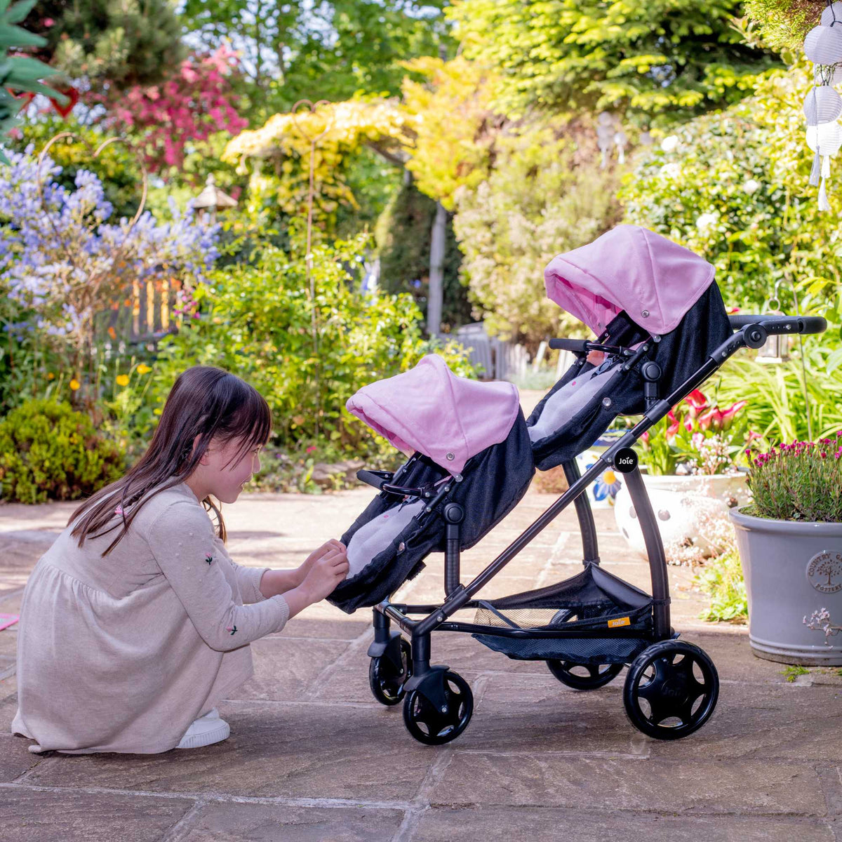 Joie Evalite Twin Dolls Pram with 9 play modes, featuring a stylish design in pink and black, adjustable handle height, swivel wheels, and a large storage basket, perfect for versatile and imaginative play with dolls.