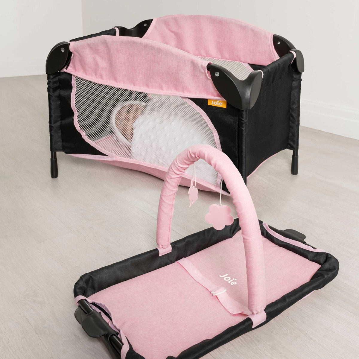 Joie Sleep &amp; Dream Dolls Travel Cot, a compact and foldable design in pink and grey, featuring breathable mesh sides and a sturdy frame, ideal for children to use for their dolls during playtime and travel