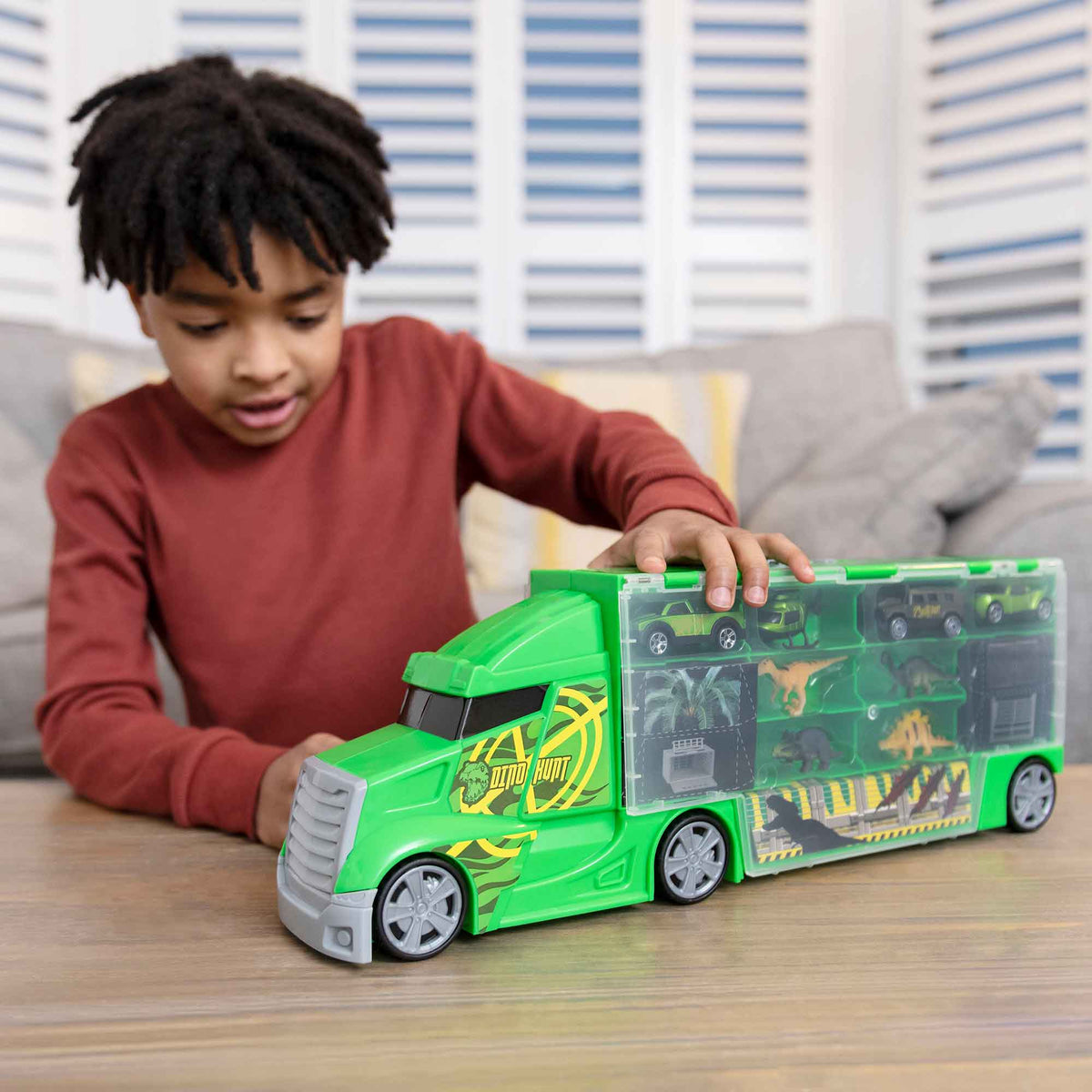 Dinosaur-themed Transporter Truck, a durable toy car carrier for kids who love racing cars and dinosaurs. Features free-moving wheels, a carry handle, and storage for a mess-free, portable play experience.